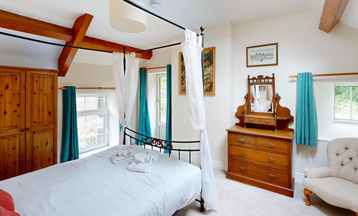 Bright master bedroom featuring a four-poster bed, skylight, and traditional furnishings.